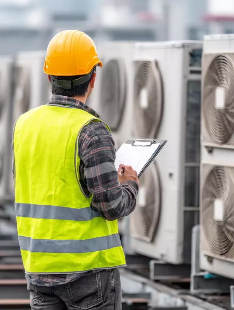 Surveyer on roof of building inspecting industrial HVAC Units.